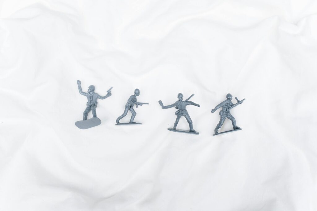 Four toy soldier figures arranged on a white background, offering a playful scene.